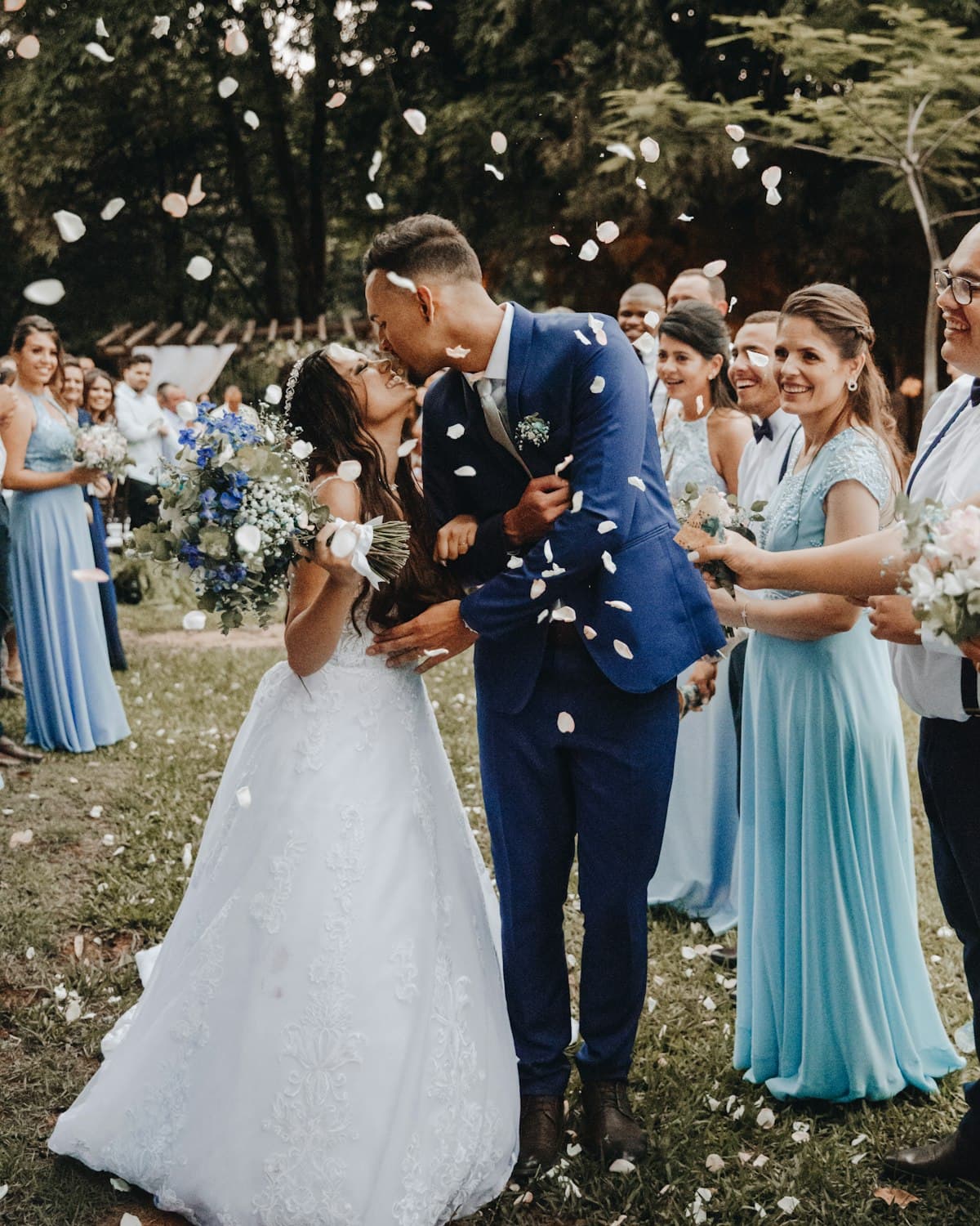 Newlyweds kissing in a shower of petals, surrounded by guests